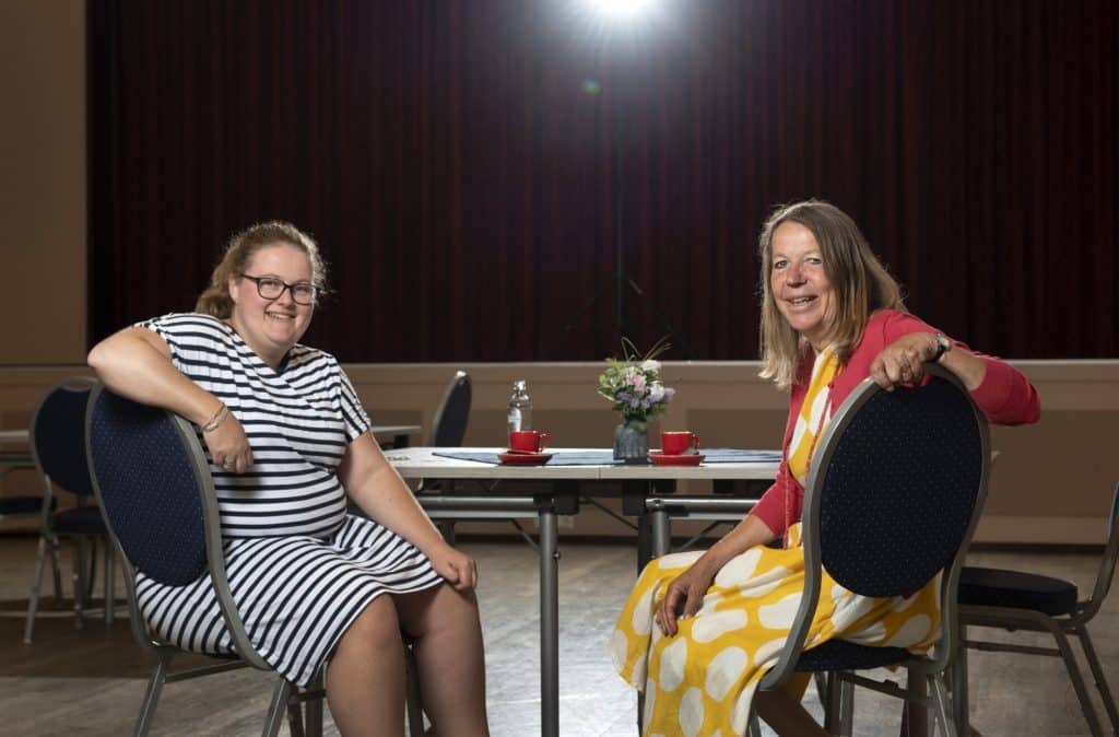 Twee mensen zittend aan een tafel in een verkiezingslokaal