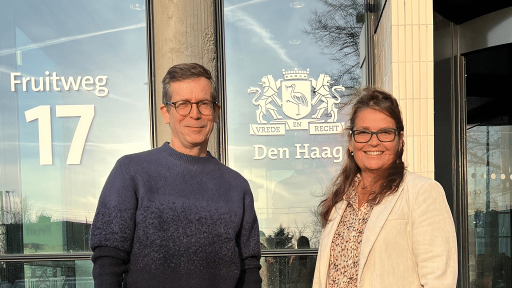 Twee mensen voor het gebouw Fruitweg 17 met logo gemeente Den Haag