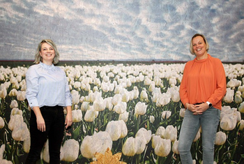 Foto van Marleen Ton (links) en Marina Rolvink met een tulpenveld op achtergrond
